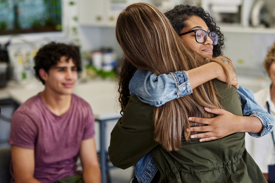two women hug during a group therapy session